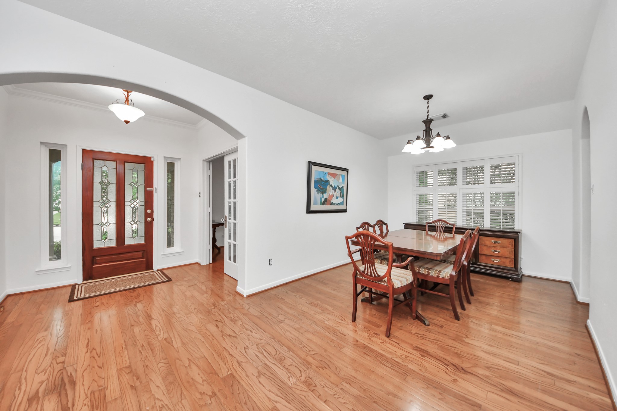 5622 Pineaster Pointe Lane Spring, TX 77379 - Photo 9 of 40 Hardwood flooring throughout, featuring a substantial arched entryway, a decorative front door with side lites, white French doors, and a window with white louvered shutters
