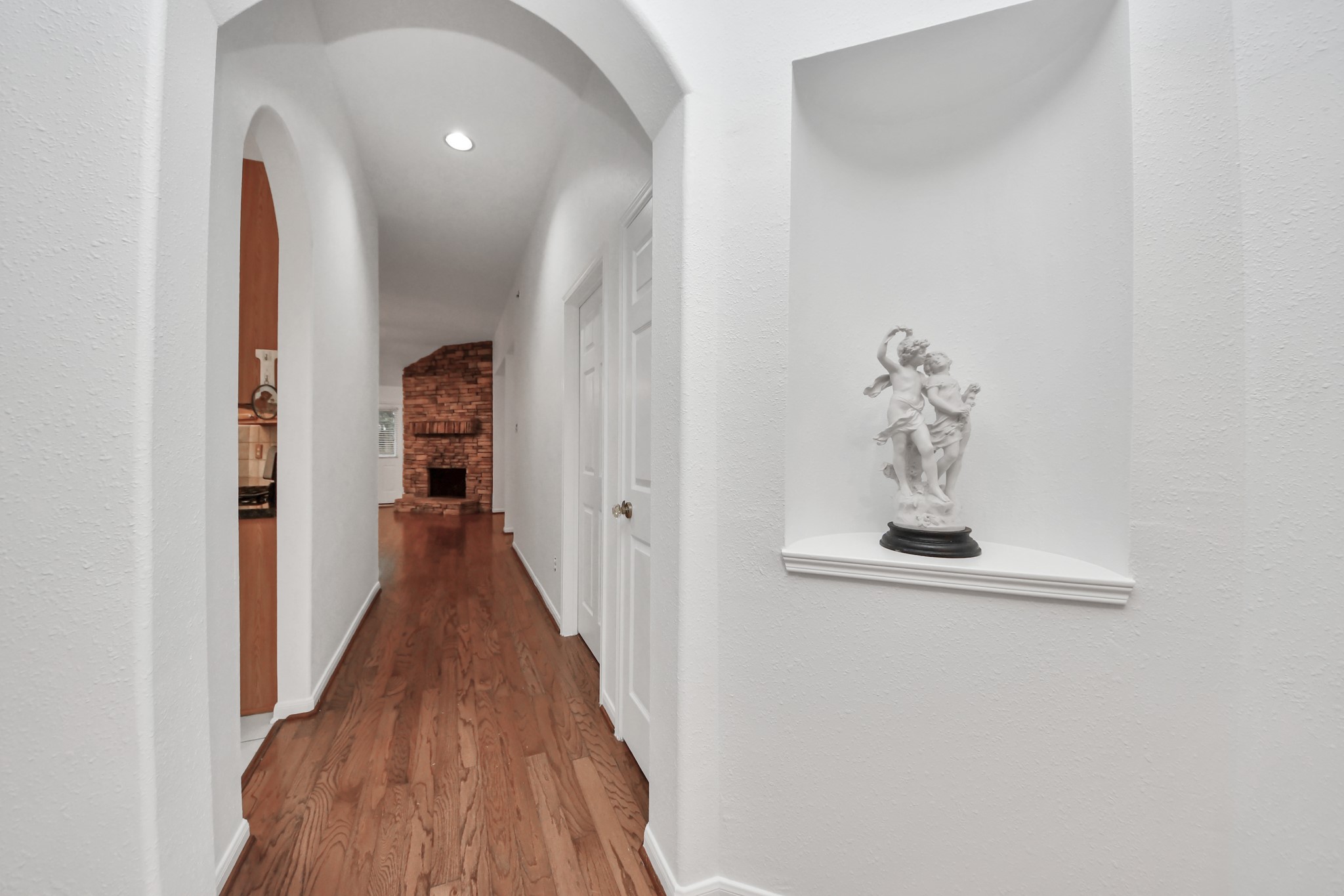 5622 Pineaster Pointe Lane Spring, TX 77379 - Photo 10 of 40 Hallway featuring wood-finish flooring and arched entryways