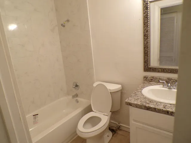 a bathroom with a granite countertop toilet a sink and a bathtub