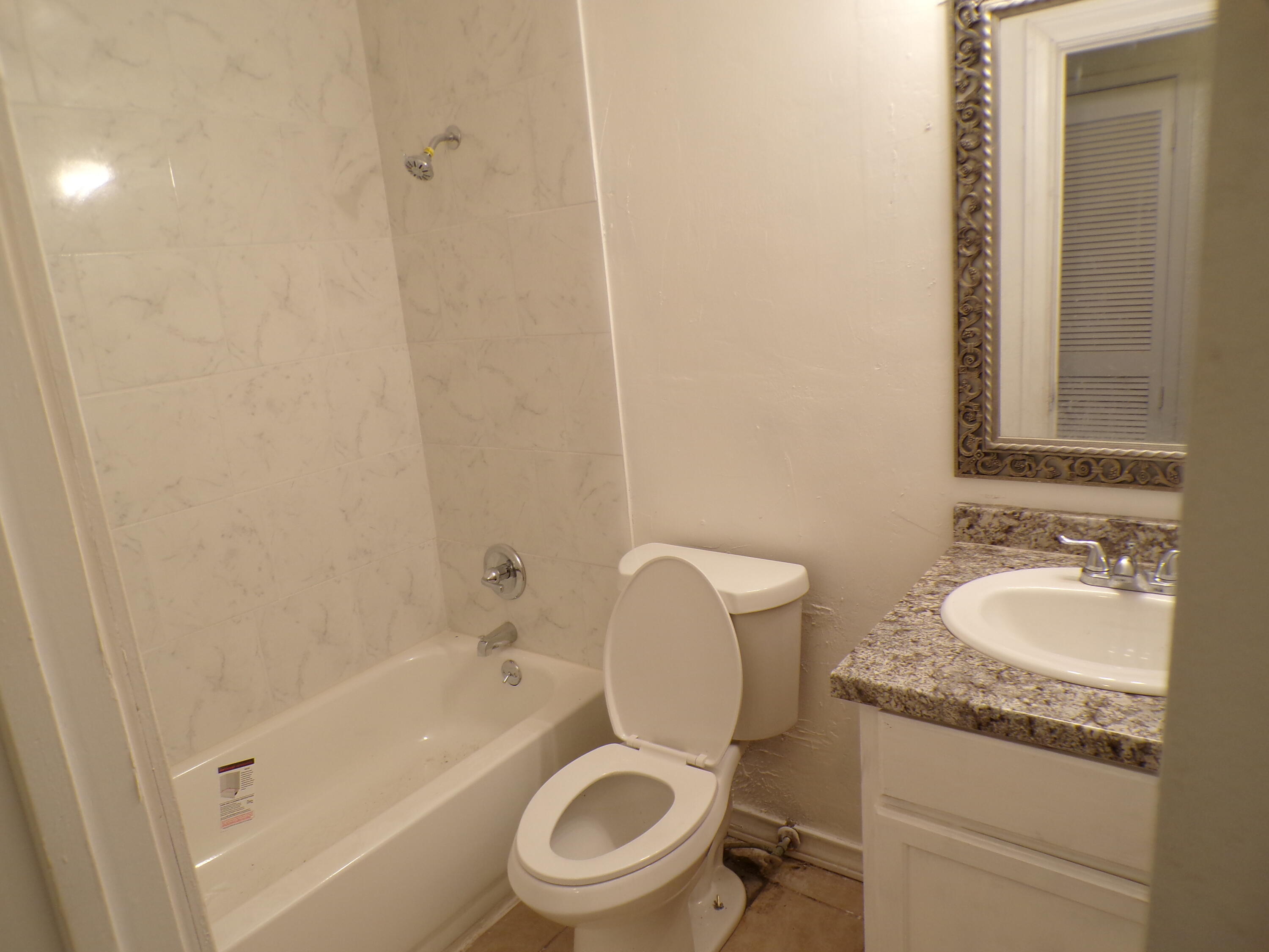 5916 14th Street Lubbock, TX 79416 - Photo 6 of 22 a bathroom with a granite countertop toilet a sink and a bathtub