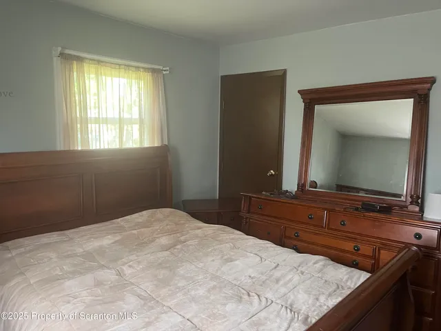 a bedroom with a bed and a mirror on dresser