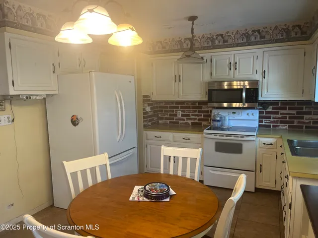 a kitchen with stainless steel appliances granite countertop a sink a stove a dining table and chairs