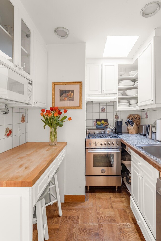 205 West 57th Street, Unit 11CD Manhattan, NY 10019 - Photo 7 of 15 a kitchen with granite countertop white cabinets and white appliances