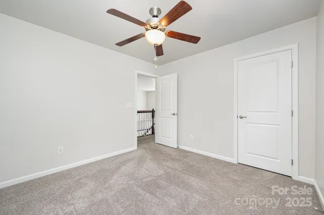 an empty room with closet and a ceiling fan