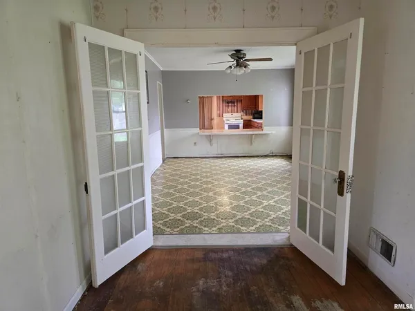 a view of empty room with wooden floor and fan