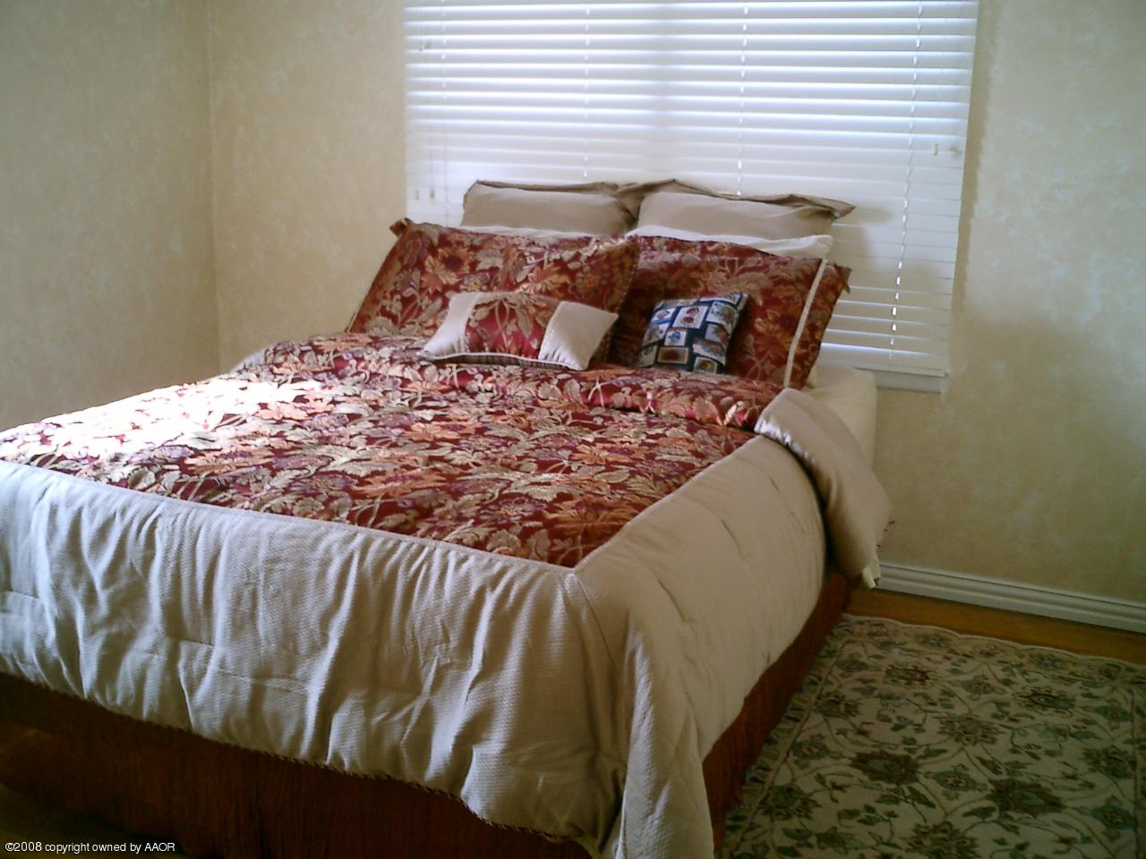 4319 South Hayden Street Amarillo, TX 79110 - Photo 4 of 13 a bed sitting in a bedroom next to a window