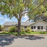 a front view of a house with a garden and trees