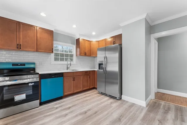 a kitchen with stainless steel appliances granite countertop a refrigerator a stove and a sink with wooden floor