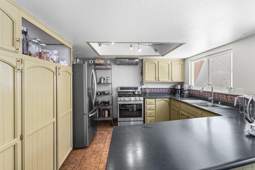 3340 Skytrail Ranch Road Jamul, CA 91935 - Photo 10 of 38 a kitchen with stainless steel appliances granite countertop a refrigerator a sink dishwasher a stove and a dining table with wooden floor
