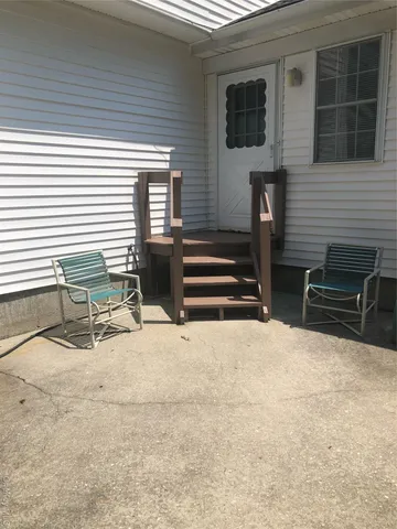a view of a house with a barbeque and wooden stairs