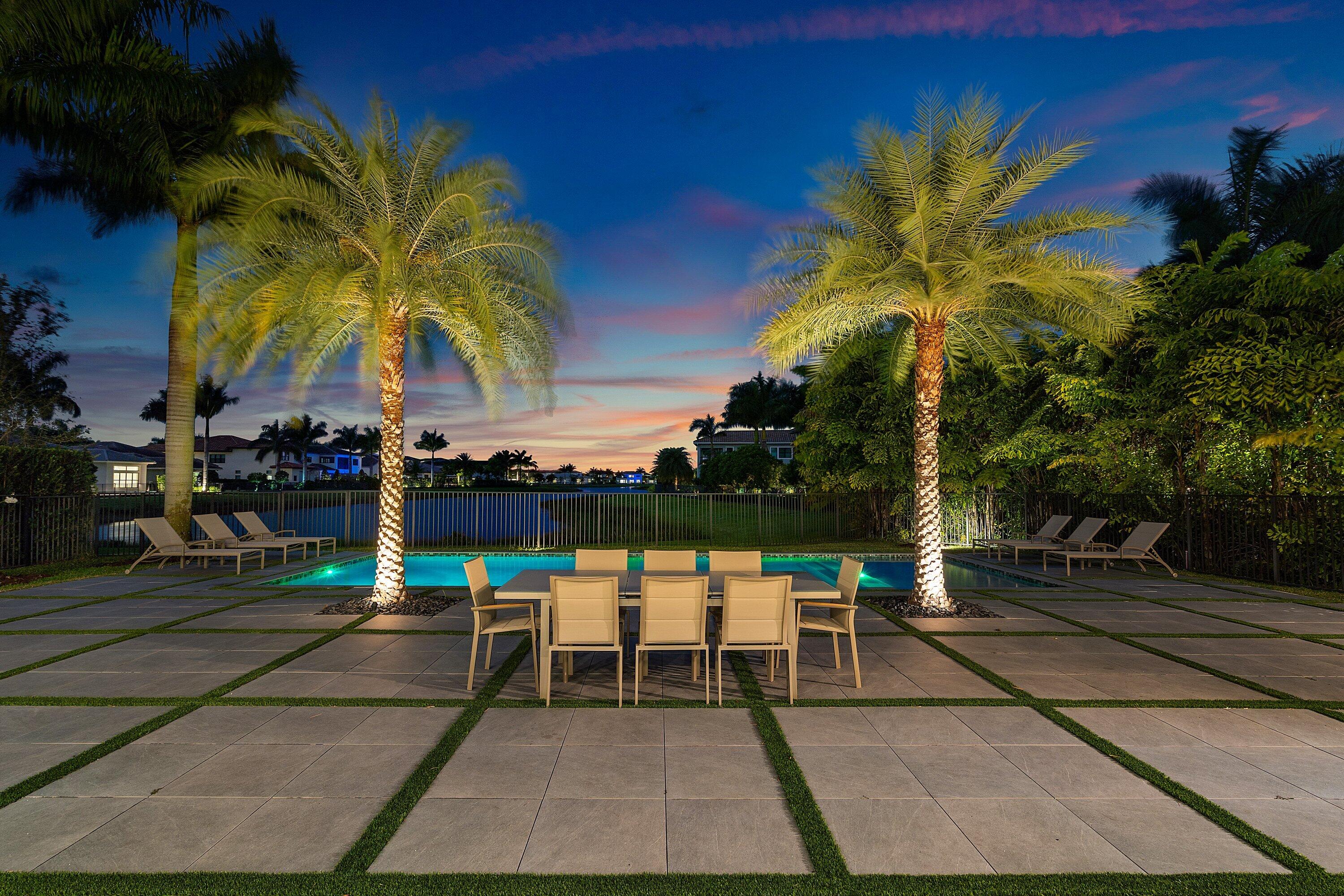 17353 Rosella Road Boca Raton, FL 33496 - Photo 71 of 77 a view of a swimming pool with a table and chairs under an umbrella with palm trees