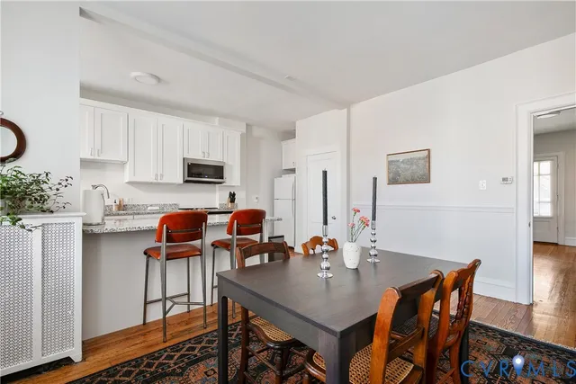 a kitchen with stainless steel appliances granite countertop a stove top oven a dining table and chairs with wooden floor