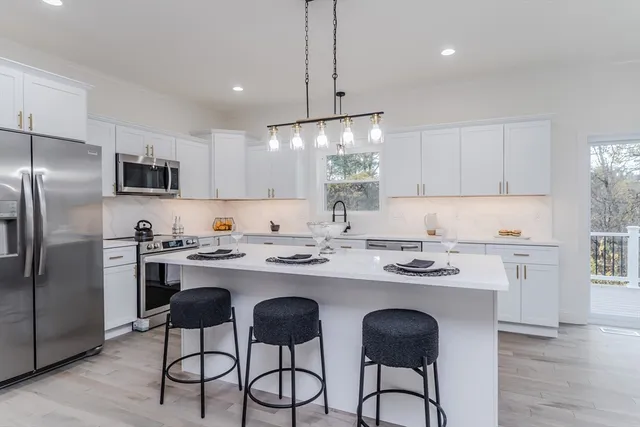 a kitchen with stainless steel appliances granite countertop a sink a stove a refrigerator and island with wooden floor