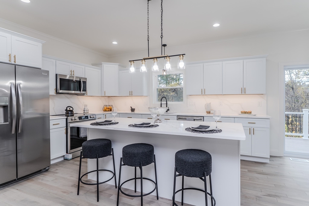 a kitchen with stainless steel appliances granite countertop a sink a stove a refrigerator and island with wooden floor