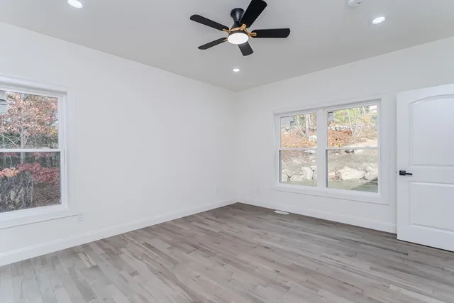 a view of an empty room with wooden floor and a window
