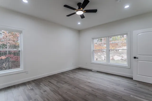 a view of an empty room with wooden floor and a window