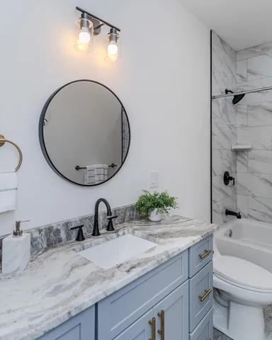 a bathroom with a granite countertop sink a toilet and a mirror
