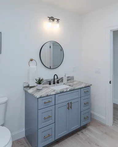 a bathroom with a granite countertop toilet sink and mirror