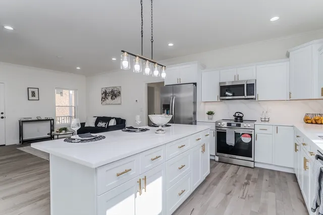 a kitchen with stainless steel appliances kitchen island granite countertop a sink stove and refrigerator