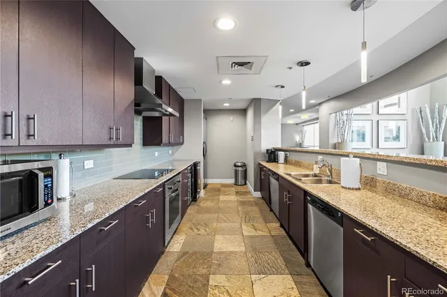 a large kitchen with stainless steel appliances granite countertop a large counter top a stove and a sink