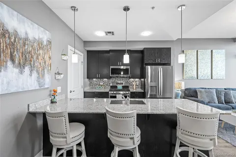 a kitchen with a dining table chairs sink and granite counter top