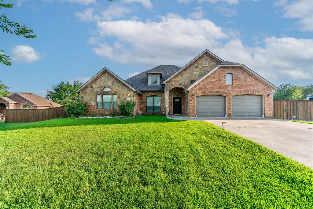View of front facade with fence, brick siding, driveway, a garage, and a front yard