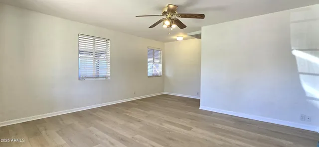 an empty room with windows and fan