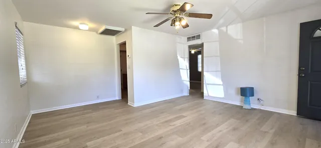 a view of empty room with wooden floor and ceiling fan