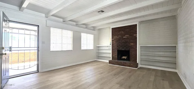 a view of an empty room with a window and fireplace