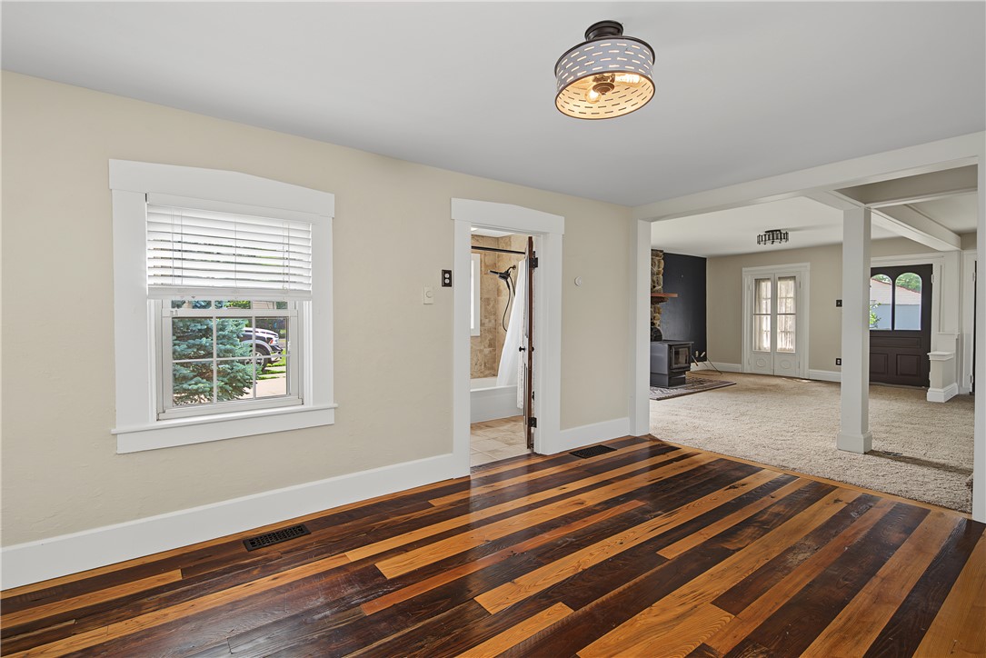 8707 Lytle Ferry Road Waynesville, OH 45068 - Photo 13 of 54 Rich hardwood flooring stretches across an inviting living space with an adjoining bathroom and a cozy fireplace beyond.