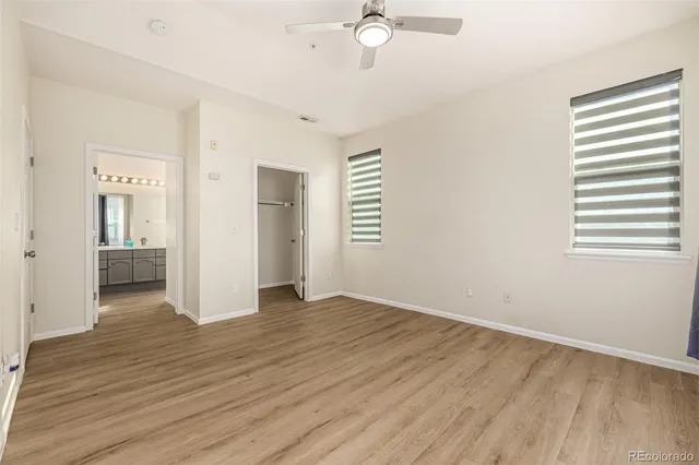 an empty room with wooden floor cabinet and windows
