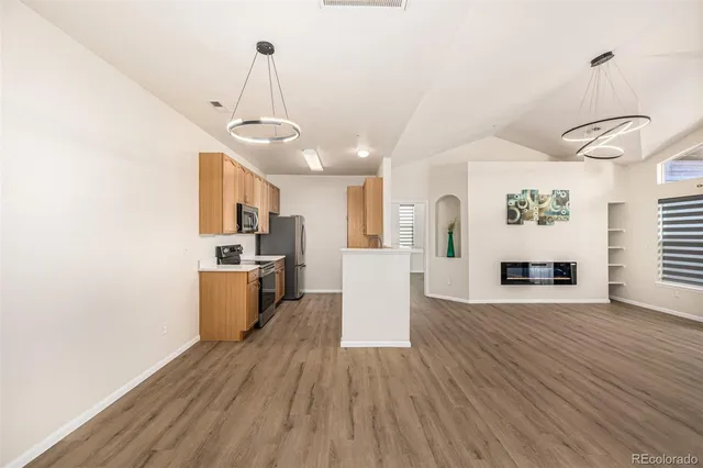 a view of a kitchen and an empty room with wooden floor