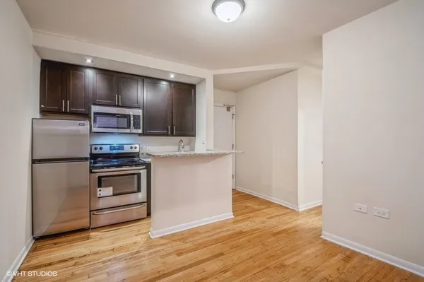 a kitchen with granite countertop a refrigerator and a stove top oven