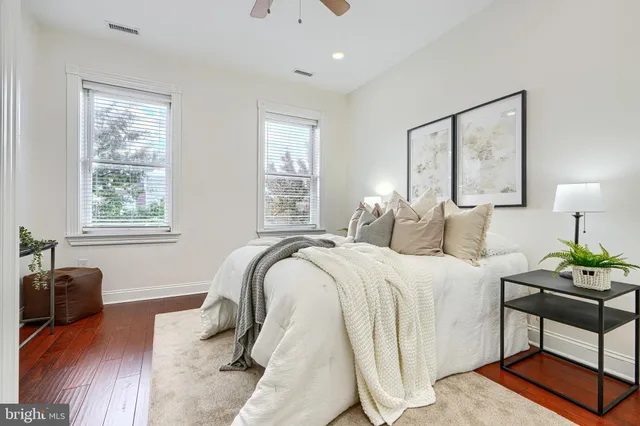 a bedroom with a bed and a potted plant on the dresser