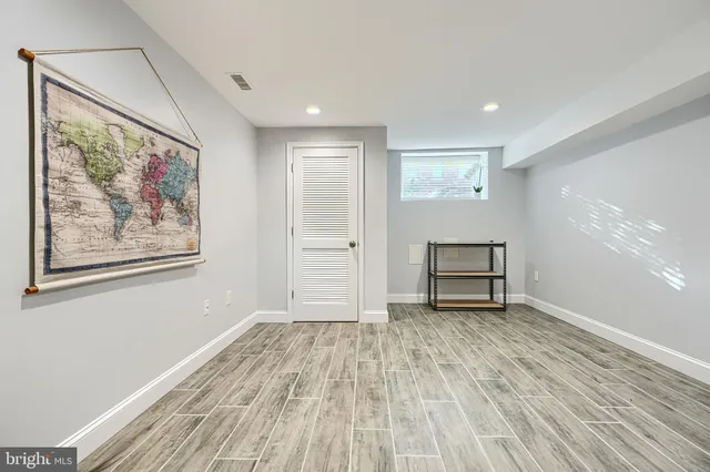 a view of an empty room with wooden floor and closet