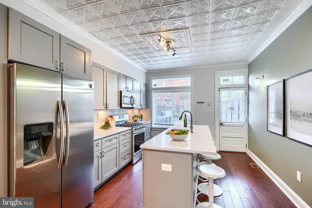 a kitchen with granite countertop a sink a stove a oven a dining table and chairs with wooden floor