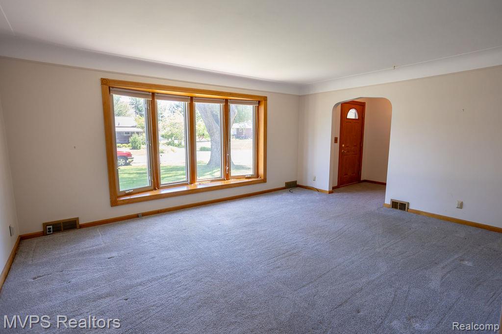 33033 Edgegrove Road Fraser, MI 48026 - Photo 7 of 20 Living area featuring a large bay window with wood trim, neutral wall tones, and gray carpeting