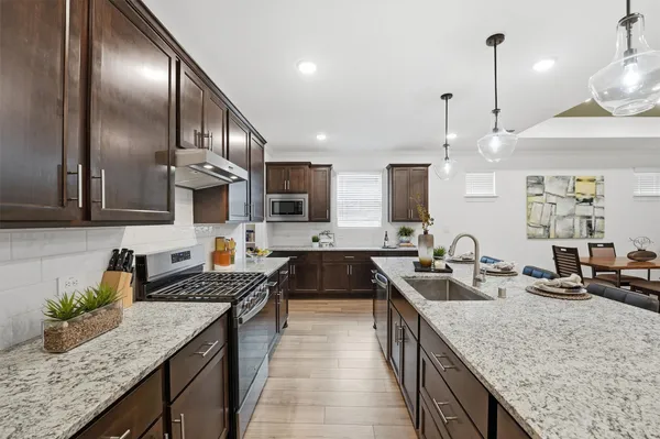 a kitchen with granite countertop stainless steel appliances a sink a stove top oven a counter space and cabinets