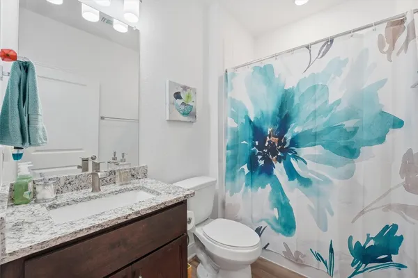 a bathroom with a granite countertop sink a toilet and a mirror
