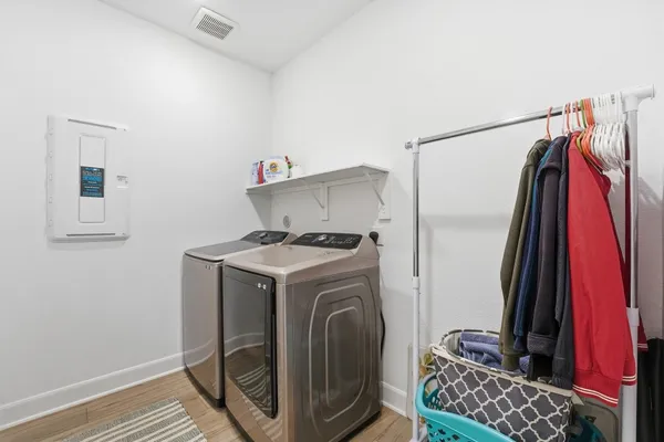 a living room with couches and kitchen view with wooden floor
