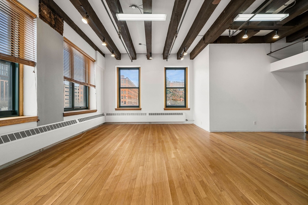 259 A Street, Unit 21 Boston, MA 02210 - Photo 3 of 18 an empty room with wooden floor and windows