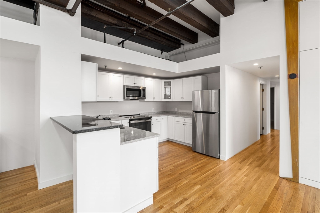 259 A Street, Unit 21 Boston, MA 02210 - Photo 8 of 18 a kitchen with stainless steel appliances granite countertop a refrigerator and a stove top oven