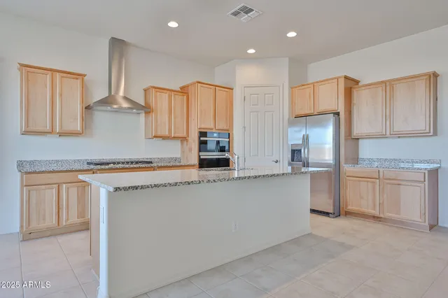 a kitchen with stainless steel appliances granite countertop a refrigerator and a stove top oven