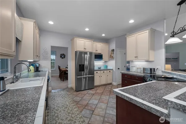 a kitchen with stainless steel appliances granite countertop a sink refrigerator and cabinets