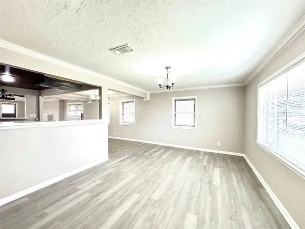 an empty room with wooden floor chandelier and windows