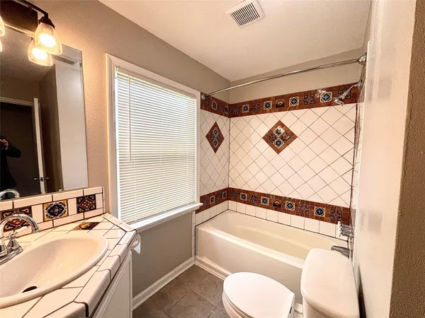 a bathroom with a granite countertop sink mirror bathtub and toilet