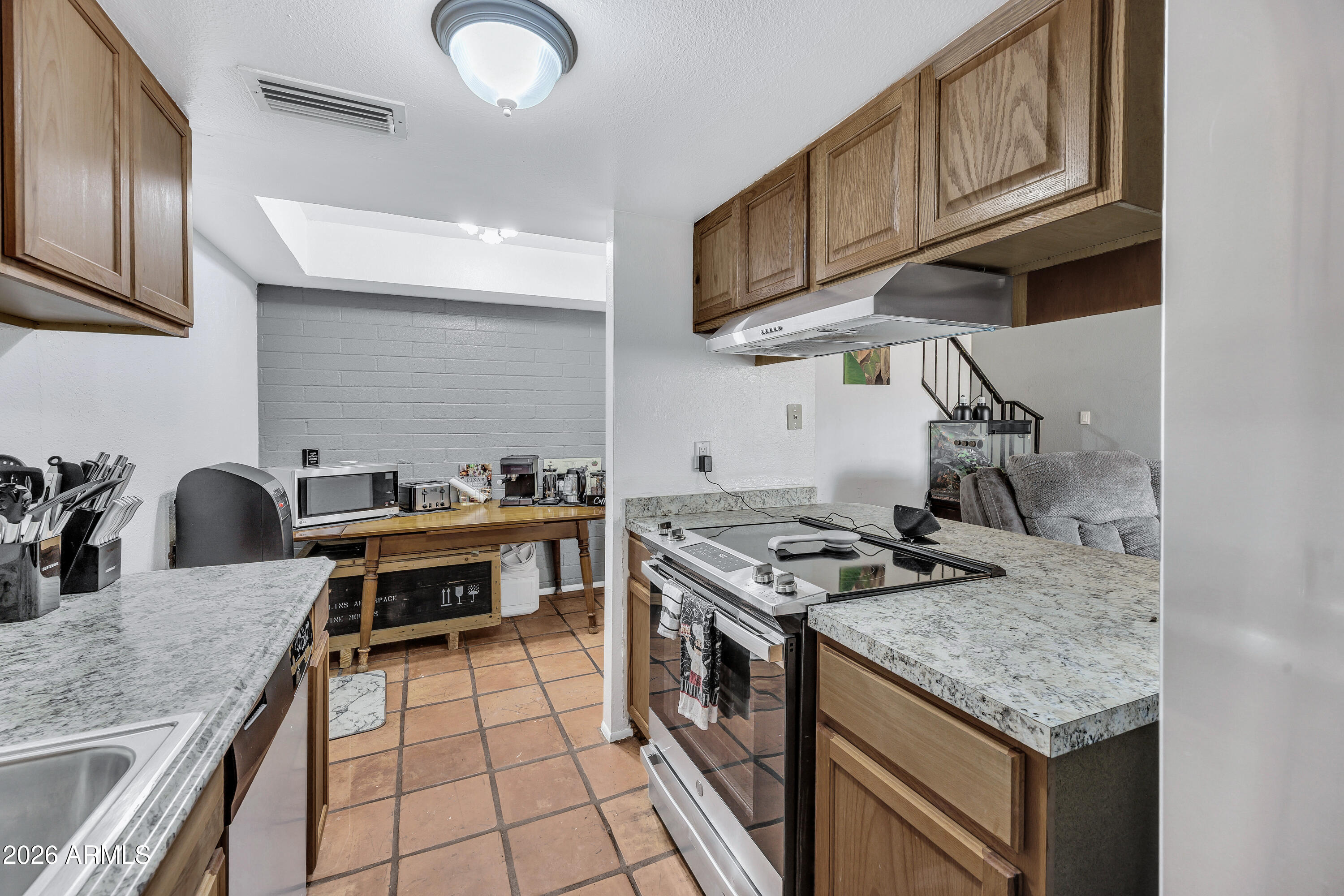 4604 East Riverside Street Phoenix, AZ 85040 - Photo 15 of 24 a kitchen with stainless steel appliances granite countertop a stove a sink and a microwave