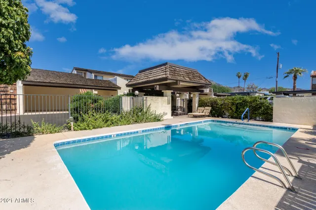 a view of a house with pool lawn chairs under an umbrella