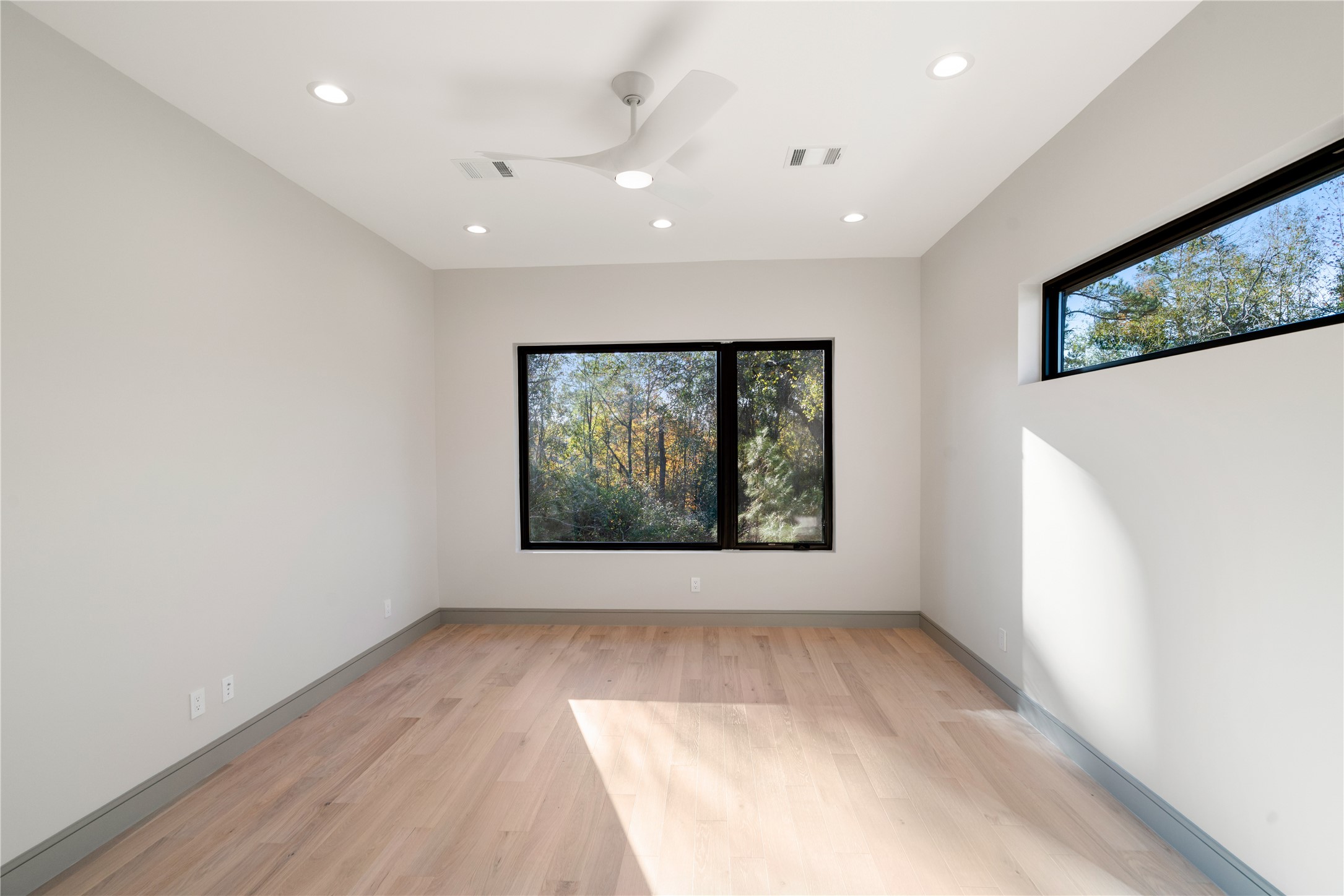 47 Pronghorn Place Spring, TX 77389 - Photo 25 of 44 This room features sleek hardwood floors, large windows offering plenty of natural light and a view of nature, recessed lighting, and a modern ceiling fan, creating a bright and inviting space.