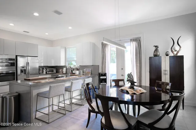 a kitchen with a dining table chairs and refrigerator